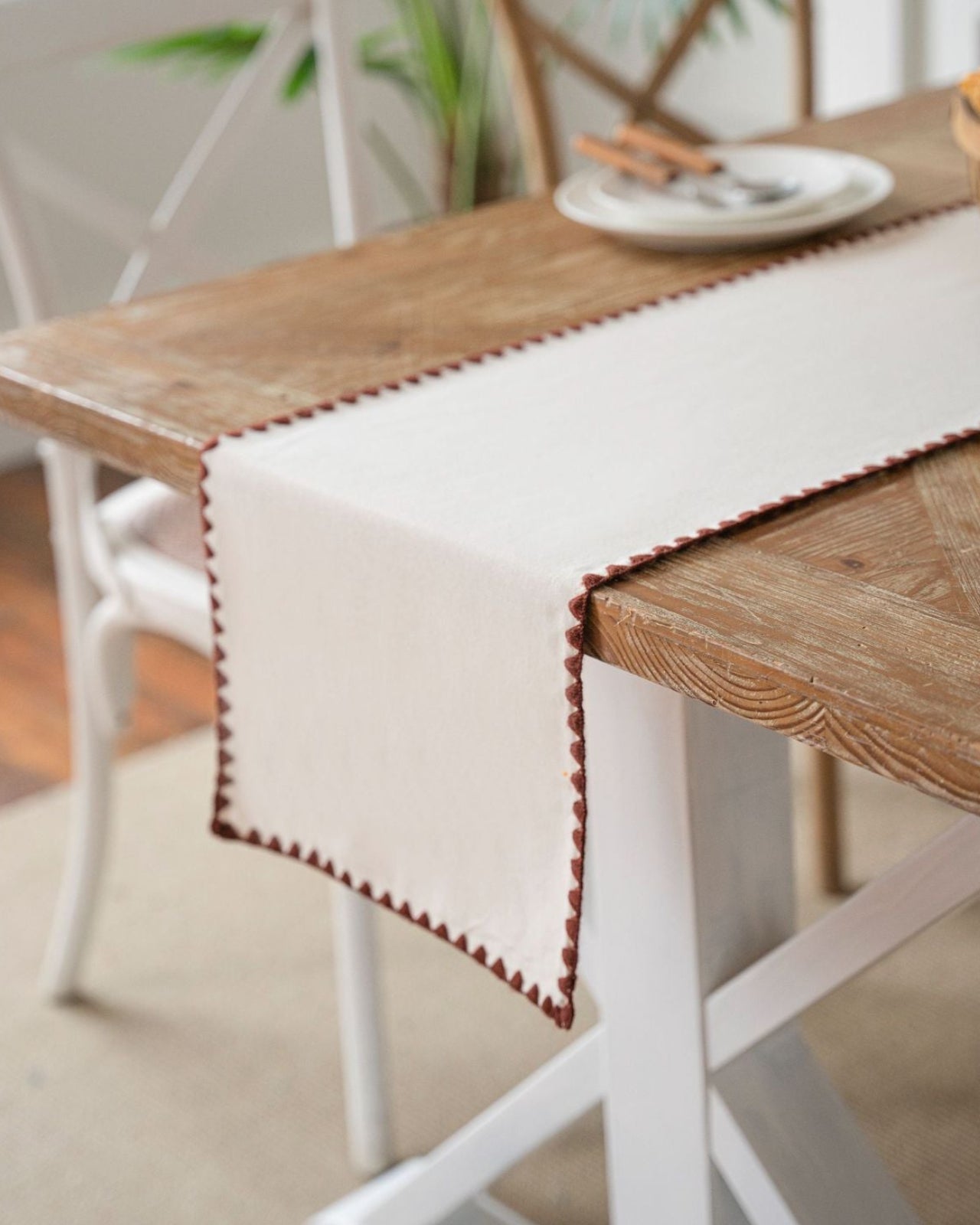 Cream table runner with crochet edge on a wooden table