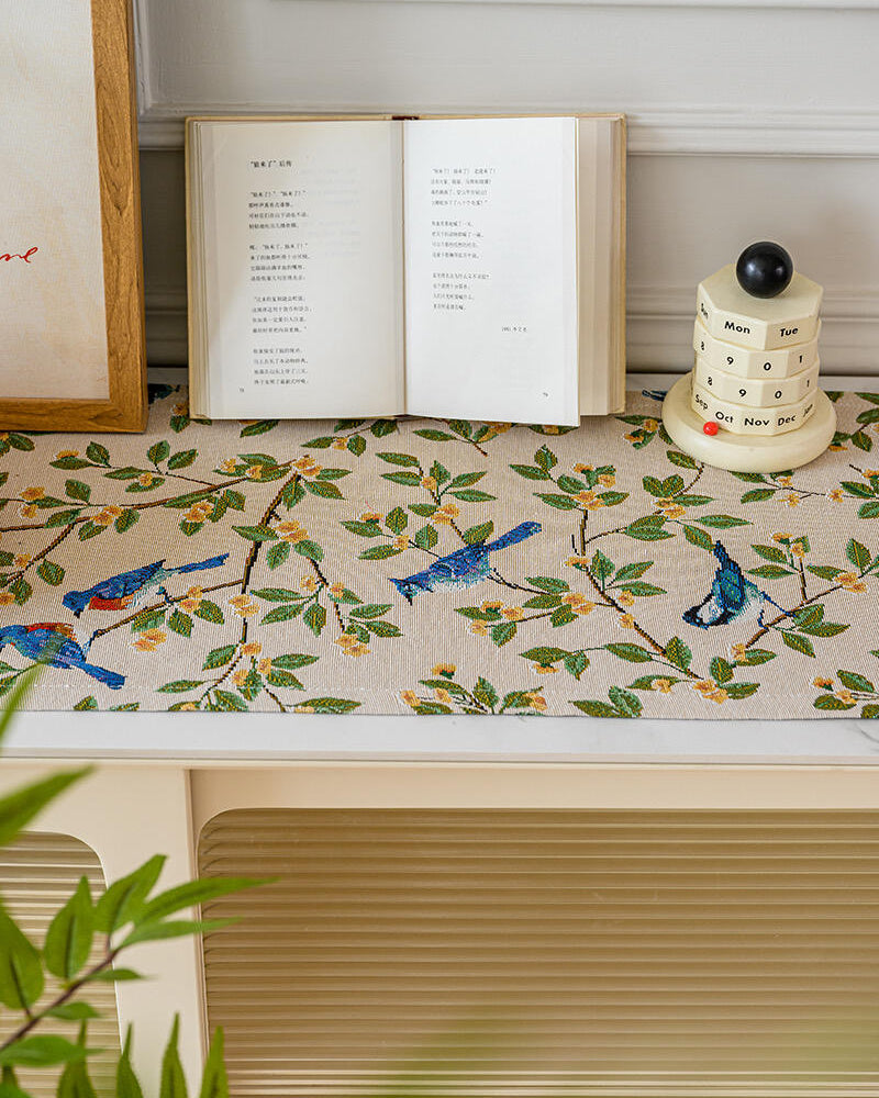 Bluebird branch table runner styled with an open book and ceramic jar