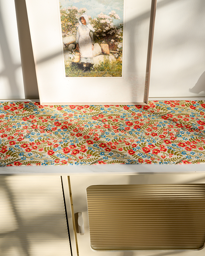 Red floral table runner on a console table with a framed picture