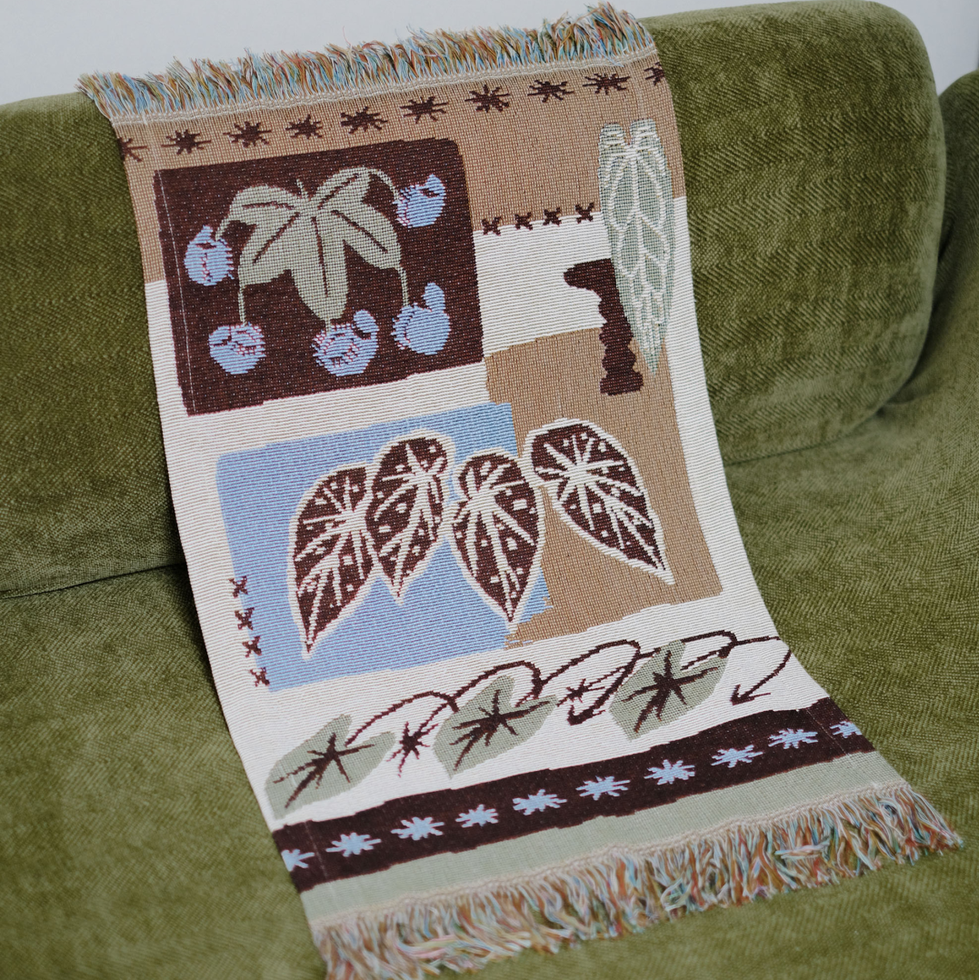 Tropical leaf woven tapestry draped over the back of a green sofa